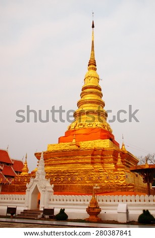 shiny golden buddhism stupa the WAT PHRA THAT CHAE HAENG CHEDI in NAN province in northern THAILAND surrounding with white wall and ceremony space in small north THAI style ornament decorated temple