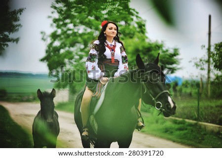 Young brunette girl on national dress with horses