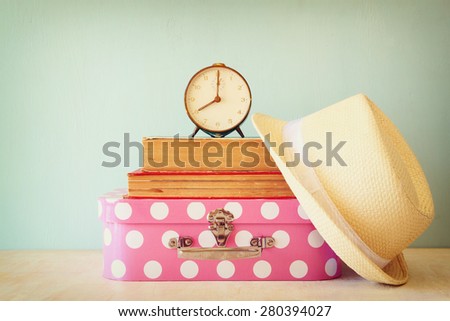 stack of  old suitcase, books and vintage clock over wooden table. retro style image