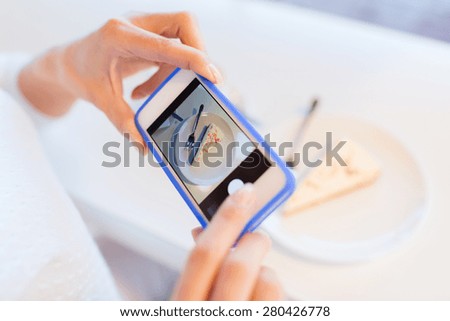 food, people, technology and lifestyle concept - close up of woman hands with smartphone taking cake picture at cafe