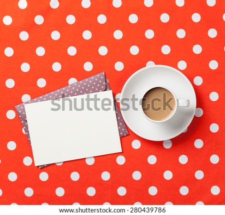 Cup of coffee and envelope on red polka dot background 