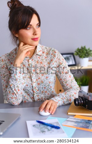Female photographer sitting on the desk with laptop 