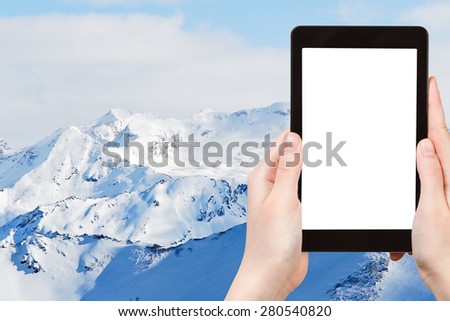 travel concept - tourist photograph snow mountains in Paradiski skiing region, Les Coches - Montchavin , France on tablet pc with cut out screen with blank place for advertising logo