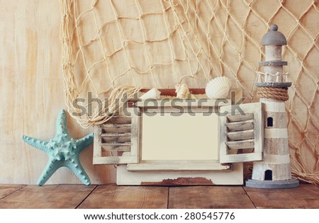 old vintage wooden white frame, starfish and lighthouse on wooden table. vintage filtered image. nautical lifestyle concept
