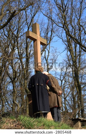 Two persons absorbed in thought in front of the Cross