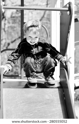 happy toddler boy on the slide of playground