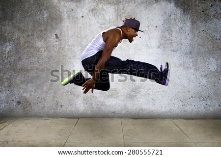 Black urban hip hop dancer jumping high on a concrete background.  The man is doing parkour or leaping. Royalty-Free Stock Photo #280555721