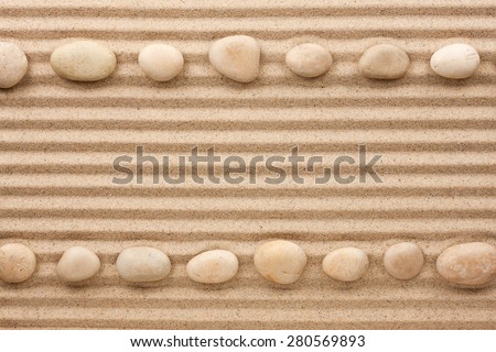 Two rows of white stones  on the sand, with space for text