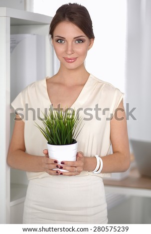 Beautiful woman holding pot with a plant .