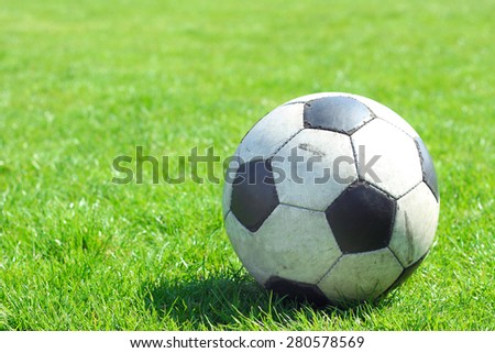 Old leather soccer ball on green grass