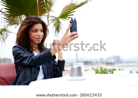 Female tourist using mobile phone camera for take a picture of herself during vacation holidays in Barcelona, stylish afro american woman taking self portrait with smart phone, feeling good and happy