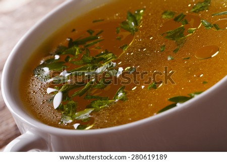 Tasty meat broth with parsley in white bowl close-up. horizontal
