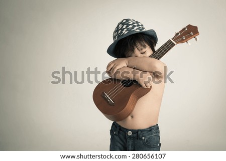 Little asian boy holding ukulele,vintage filter
