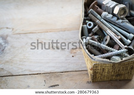 Box of old rusty metal screws on wooden background