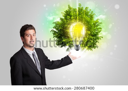 Young man presenting idea light bulb with green tree concept