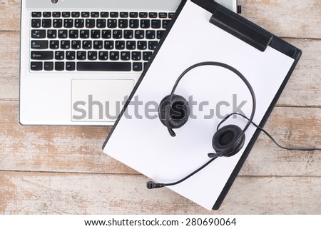 Close up top view photo of laptop, paper and headphones on the light-colored woodblocks