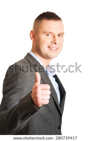 Young smiling businessman gesturing thumbs up.
