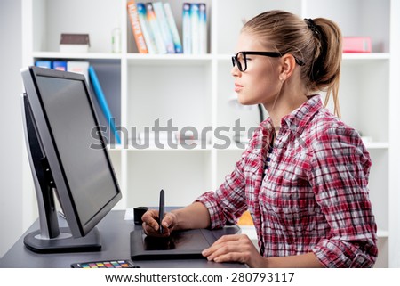 Young female graphic illustrator sketching picture. Woman designer working with tablet pc in the office. 