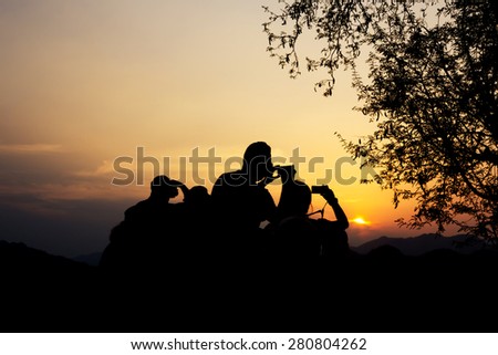 Silhouette of travelers with camera during sunset at That Phu Si and Wat tham Phu Si, Luang Prabang Laos.