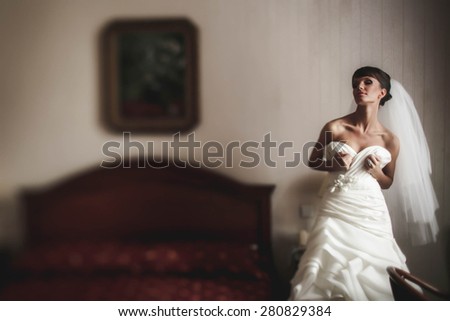 bride in wedding dress is posing  on the background  bed