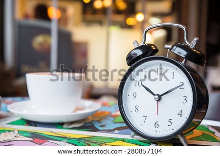Retro alarm clock with cup of cappuccino in coffee shop, coffee break time