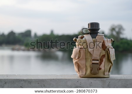 Army water canteen with desert cover with river background