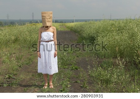 woman hiding under empty paper bag over summer background