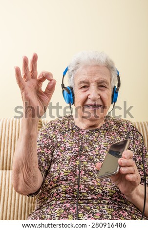 a lovely senior woman listening music (with smart phone / ipod) Royalty-Free Stock Photo #280916486