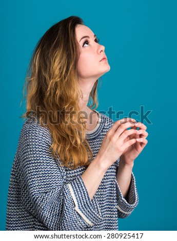 Portrait of praying young woman on a blue background