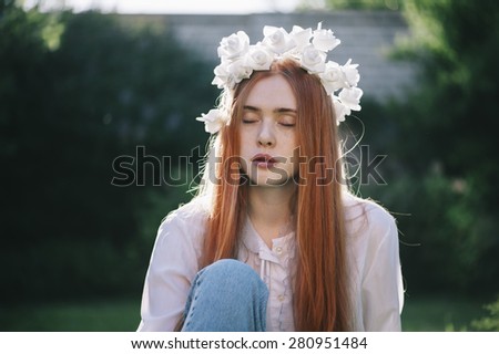 Beautiful redhead young woman with a closed eyes contemplating in a deep thought in the summer park