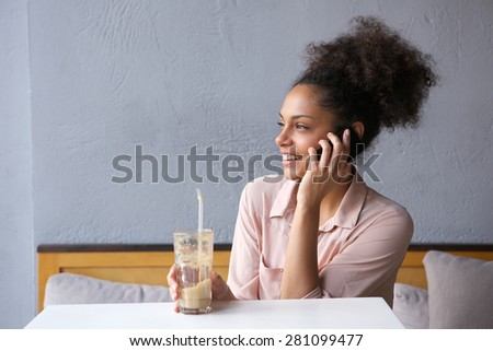 Close up portrait of a smiling young woman sitting at restaurant talking on mobile phone