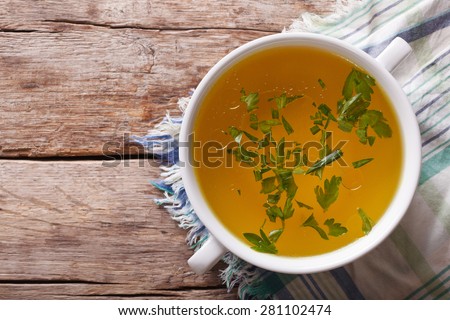 Tasty meat broth with parsley in a white bowl closeup. horizontal view from above
