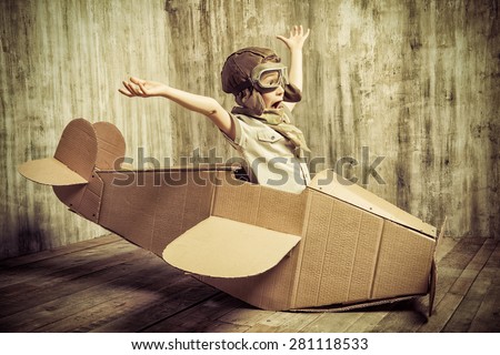 Cute dreamer boy playing with a cardboard airplane. Childhood. Fantasy, imagination. Retro style. Royalty-Free Stock Photo #281118533
