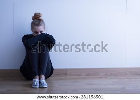 Sad woman with depression sitting on the floor Royalty-Free Stock Photo #281156501