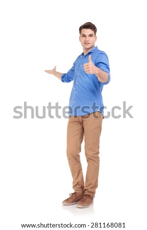 Full body picture of a young fashion man welcoming you while showing the thumbs up gesture.
