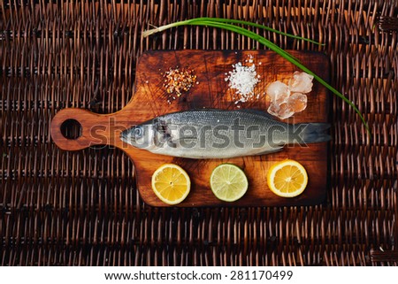 Creative picture of herring on the wooden vintage board with lemon, lime, ice, salt and pepper