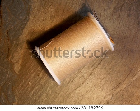 Royalty Free Photograph - Professional Tailor's Sewing Needle in a Spool of Tan Thread - Isolated Close Up Photograph - with Copy Space