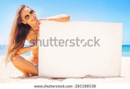 woman on a beach holding a blank board for your text