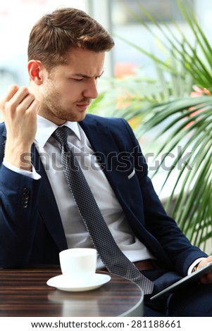 Image of happy young man using digital tablet in cafe