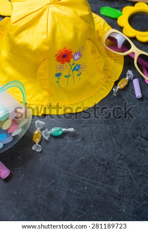 Children's summer yellow hat and chalk on black chalkboard from above. Summer vacation concept. Background with copyspace