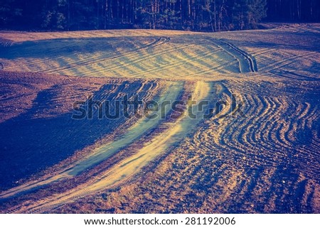 Vintage photo of plowed field in calm countryside. Agricultural landscape with old fashioned colors