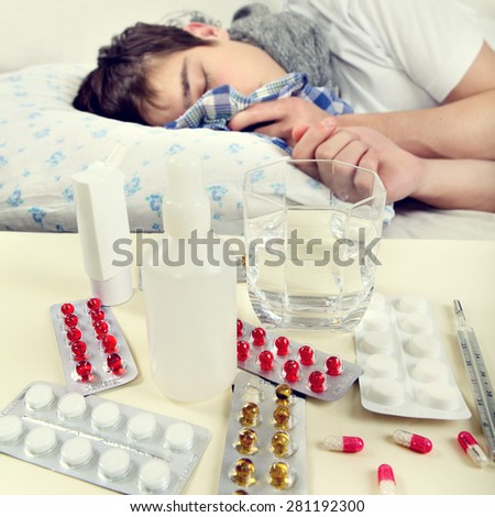 Toned Photo of Sick Young Man on the Bed. Focus on the Pills