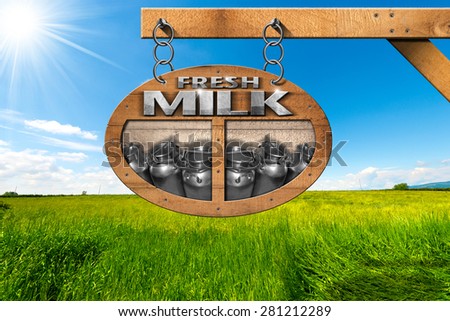 Fresh Milk - Wooden Sign in Countryside. Wooden sign with text Fresh milk, and steel cans for the transport of milk. Hanging from a metal chain on a pole in a countryside landscape