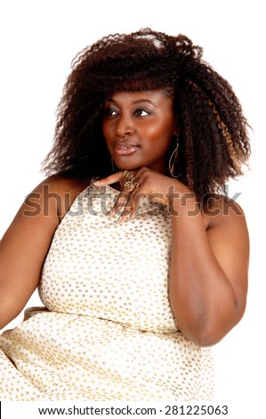 A portrait picture of a big African American woman in a beige dress with
her hand under her chin, isolated for white background.
