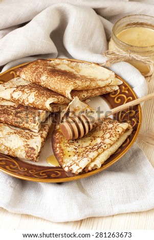 Thin pancakes, crepes with  syrup on wooden cutting board. Pancake week, mardi gras, maslenitsa holidays Royalty-Free Stock Photo #281263673