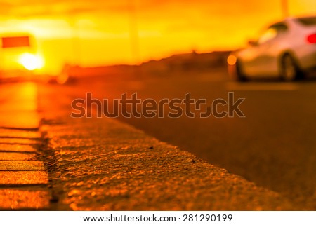 Sunset in the city. Driving car, view from the level of the dividing line, image in the orange toning
