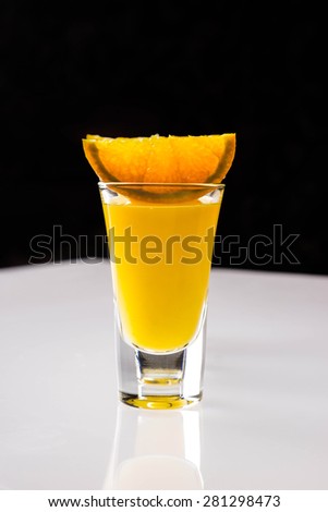 Orange juice in shot glass on the bar table