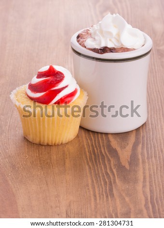 Strawberry cupcake with a cup of hot chocolate on dark wooden tabletop - anniversary or Valentine's treat to a loved one