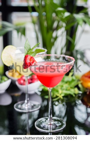mix of the bright refreshing cocktails lime and strawberry daiquiri on a table in a restaurant with decoration of salt on the edge of the glass with fresh mint and lime slices and berries. soft focus