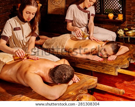 Couple  having oil Ayurveda spa treatment on exotic wooden bed.